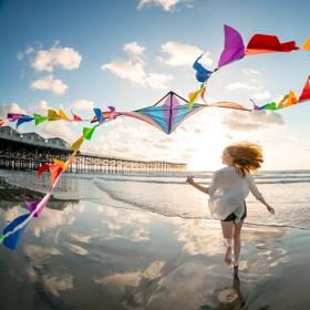 Friends fly kites on the beach by Crystal Pier in San Diego. Shot was taken as part of the 2024 Road Trips Up Around the Bend/Playful Journeys Brand campaign shoot.